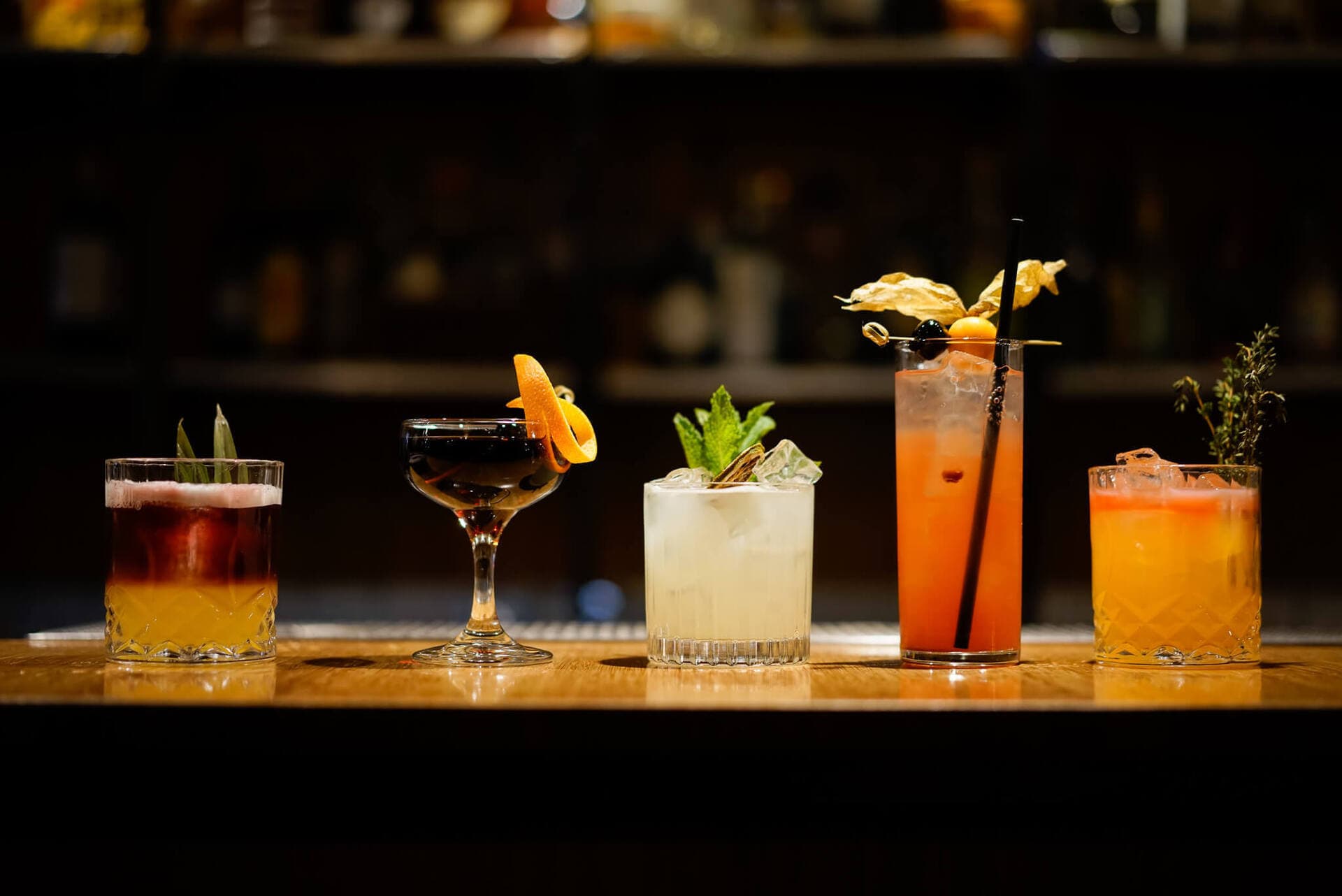 A lineup of craft cocktails along the candlelit bar at Cenote in downtown Victoria